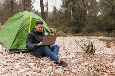 man-beside-tent-with-laptop